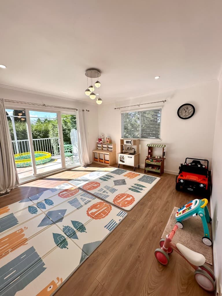 Playroom with ride-on toys, a play kitchen, and doors to the backyard